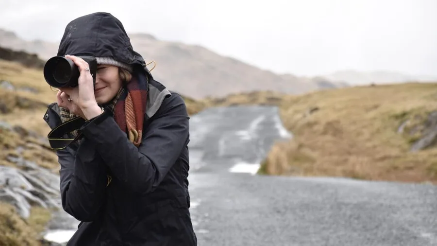 Photographer adjusting camera equipment in snowy winter landscape during outdoor shoot