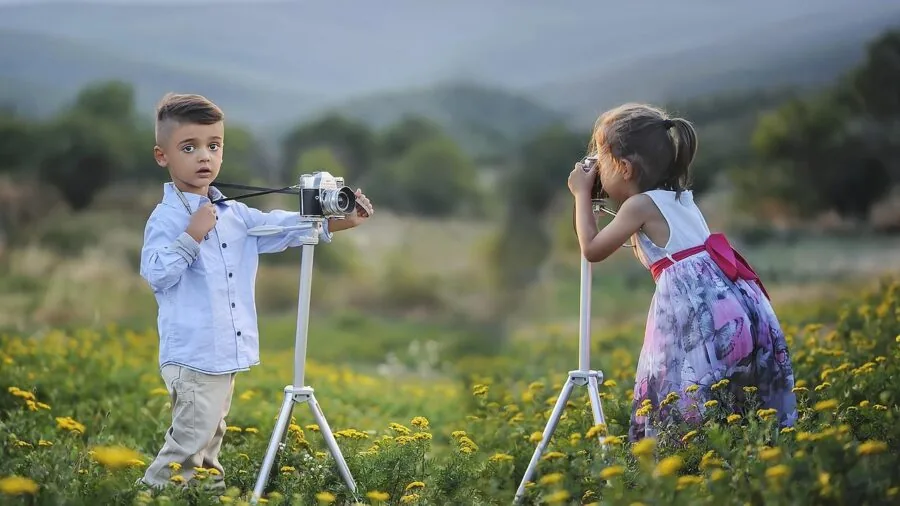 Photographer adjusting tripod leg locks while setting up camera equipment in natural outdoor environment