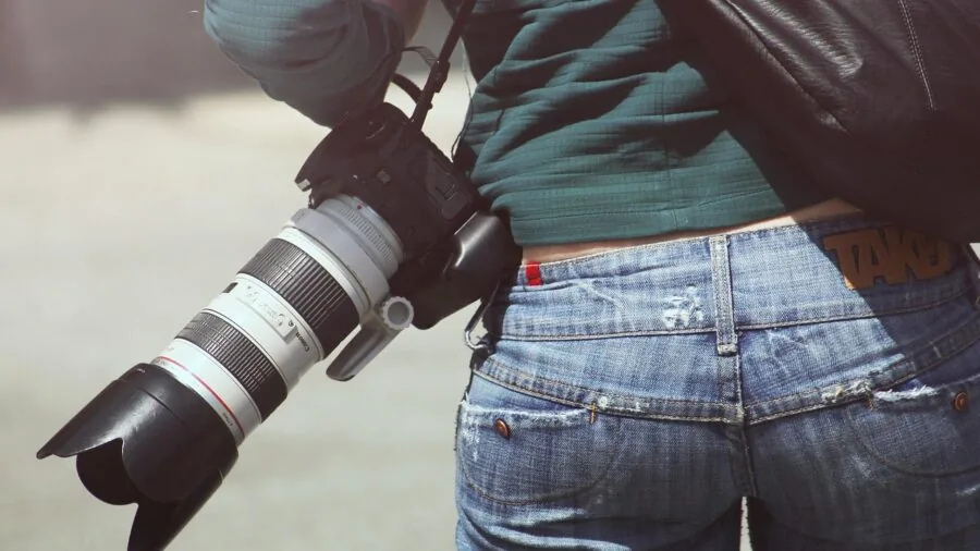Photographer gently cleaning camera lens with proper technique in natural light