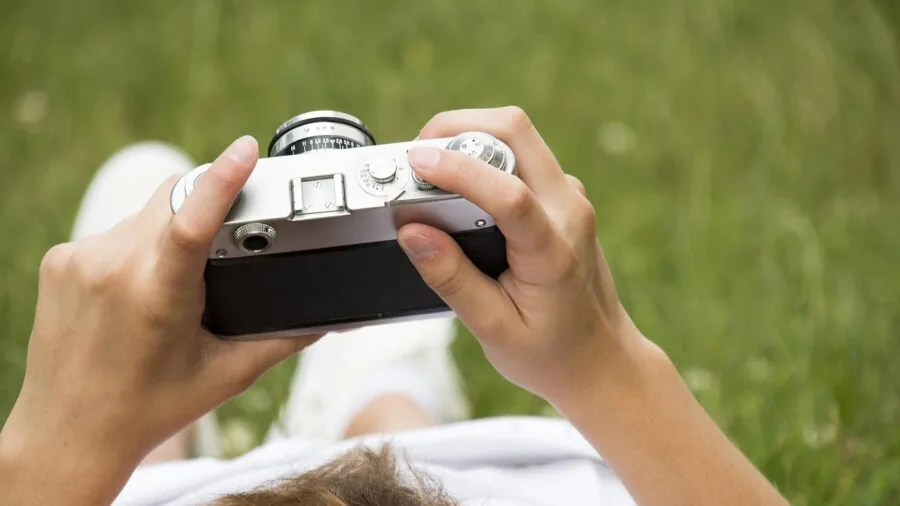 Photographer meticulously cleaning camera lens with professional tools during outdoor shoot
