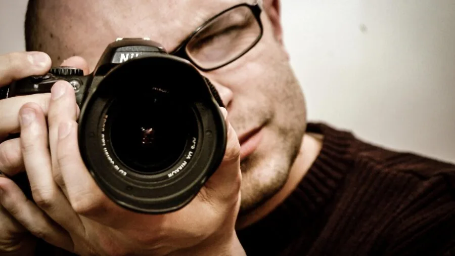 Photographer positioning large softbox light modifier in professional studio workspace