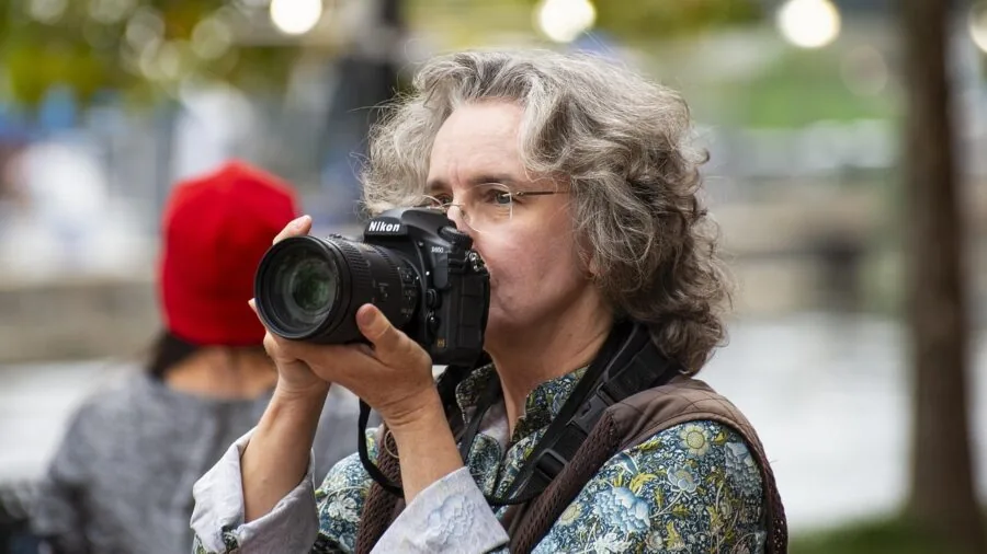Photographer reviewing camera gear and flash equipment in natural light studio setting