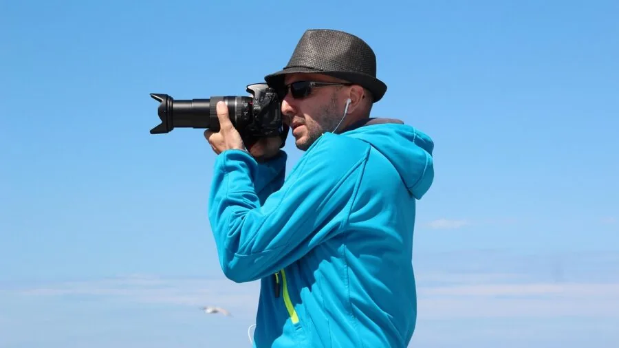 Photographer using telephoto lens to capture distant wildlife in natural landscape setting