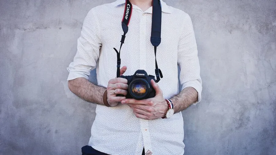 Photographer wearing textured camera strap against body during outdoor photo session