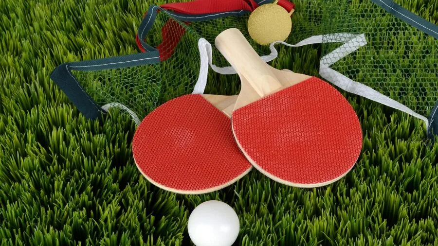 Player holding ping pong paddle during competitive match, focusing on paddle grip and technique