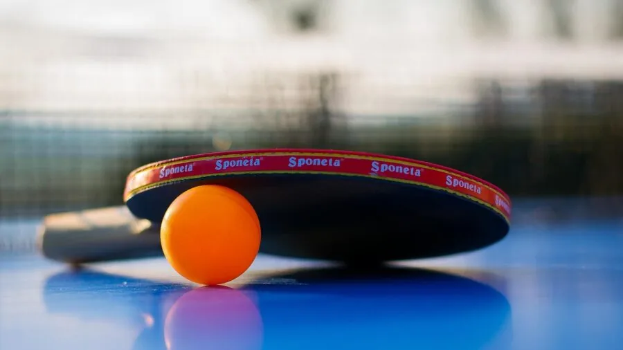 Player in action during competitive table tennis match, demonstrating paddle control and spin technique