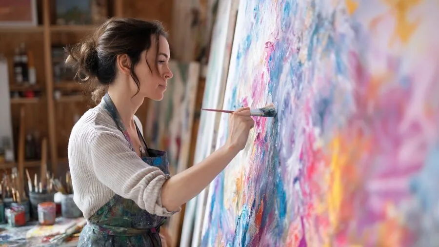 Professional artist working at easel in bright studio with natural light and canvas