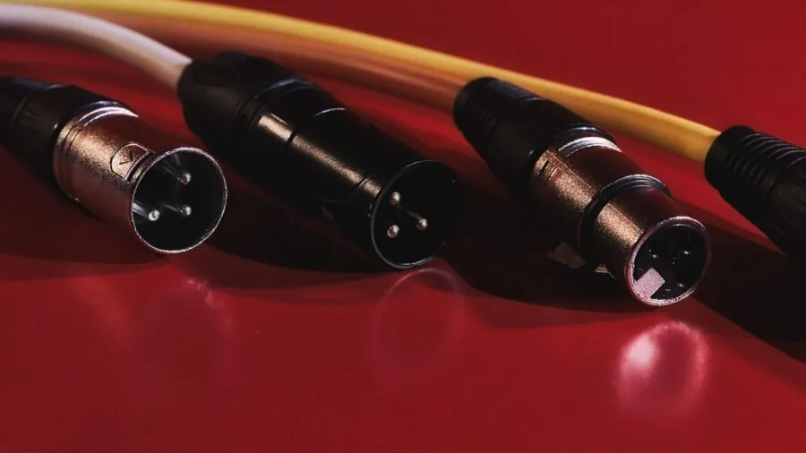 Professional audio engineer working at mixing console with XLR cables and studio equipment in recording studio