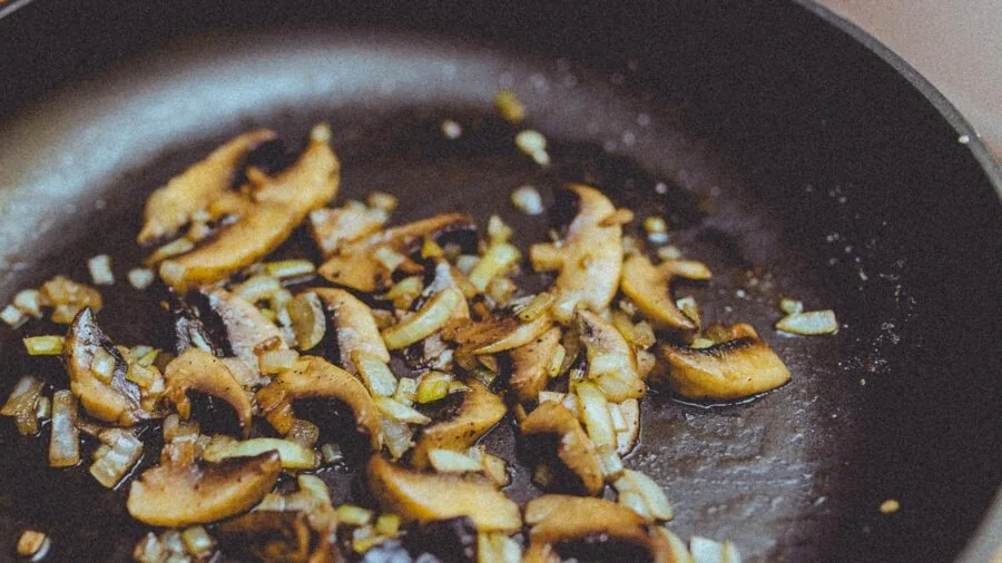 Professional cook gripping a full sauté pan with both hands in kitchen