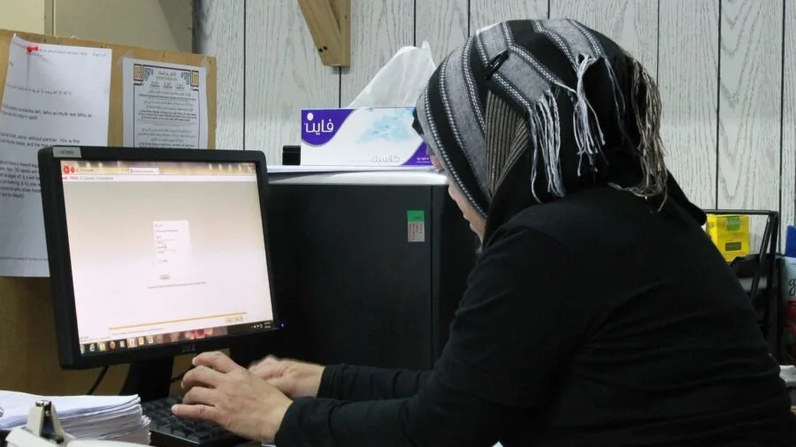 Professional dealing with jammed document at office desk showing frustration with equipment malfunction