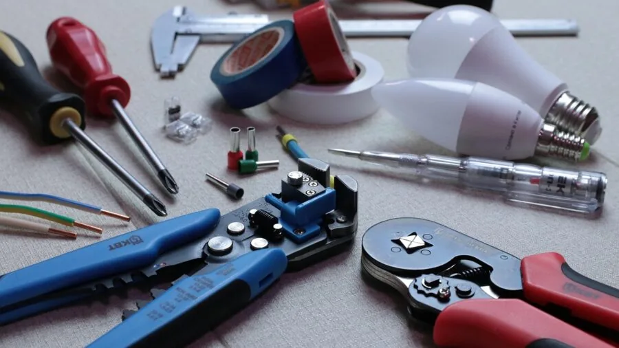 Professional electrician checking wire specifications with measuring tool on workbench