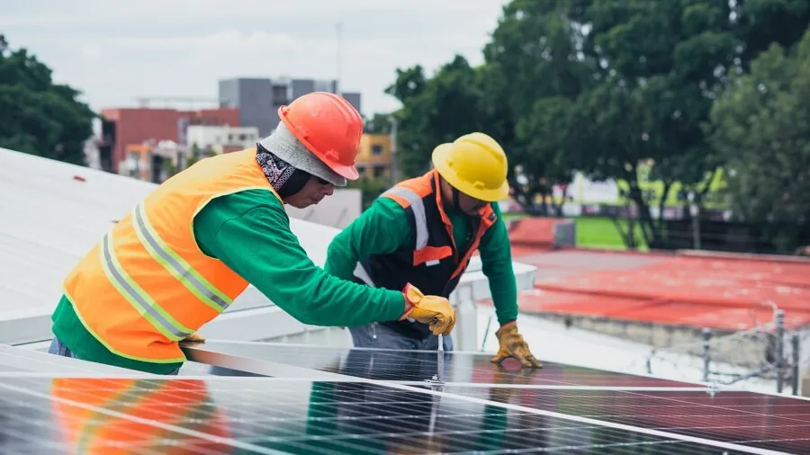 Professional installing solar panels on residential rooftop with tools and equipment in natural daylight