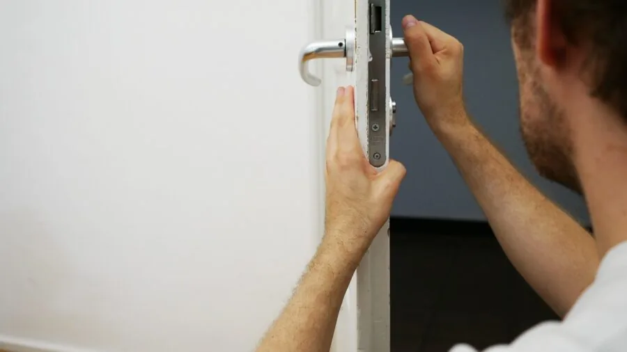 Professional locksmith rekeying a residential door deadbolt with tools
