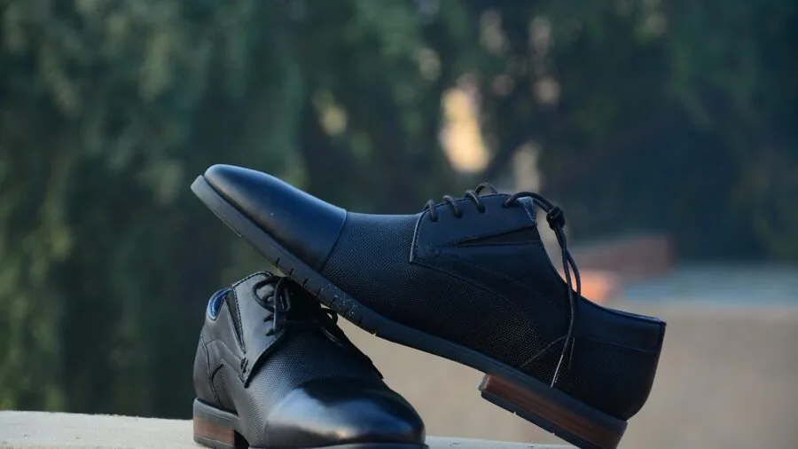 Professional man in formal black suit and dress shoes standing confidently in office setting
