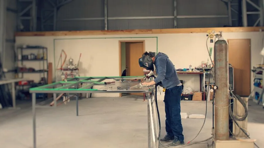 Professional metalworker in workshop using angle grinder on metal project with sparks flying