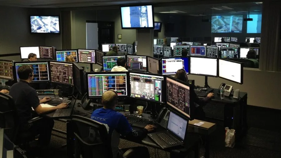 Professional monitoring center operator at desk responding to security alerts