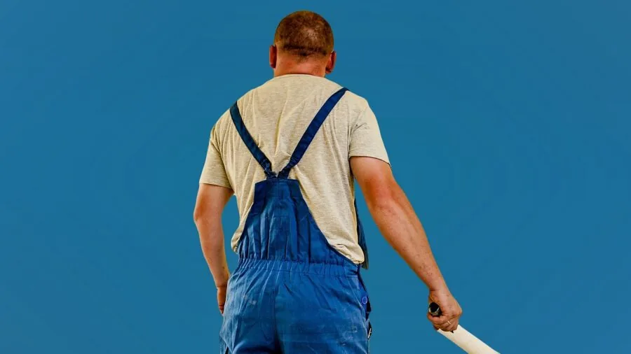 Professional painter using microfiber paint roller on interior wall in natural light