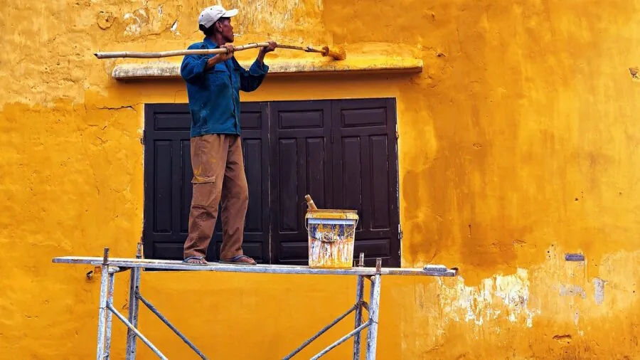 Professional painter using spray technique to apply coating on wall surface