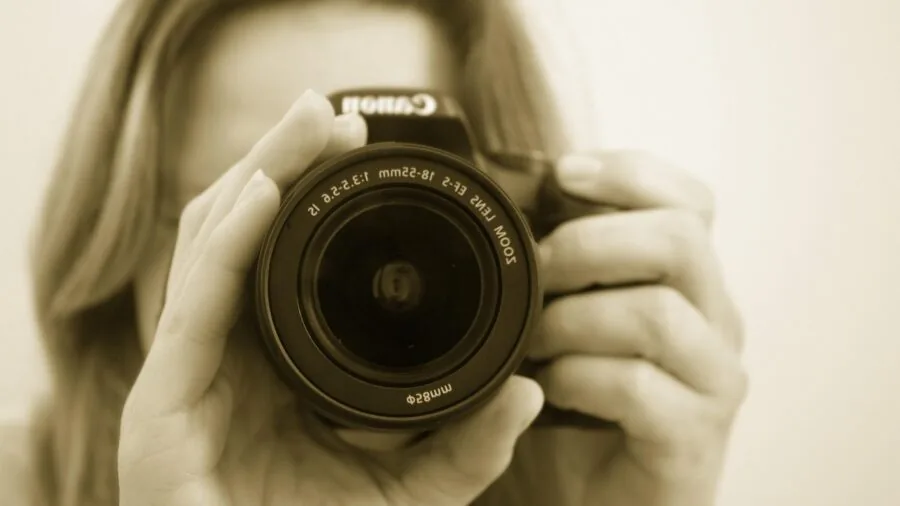 Professional photographer adjusting flash exposure settings on camera in studio environment