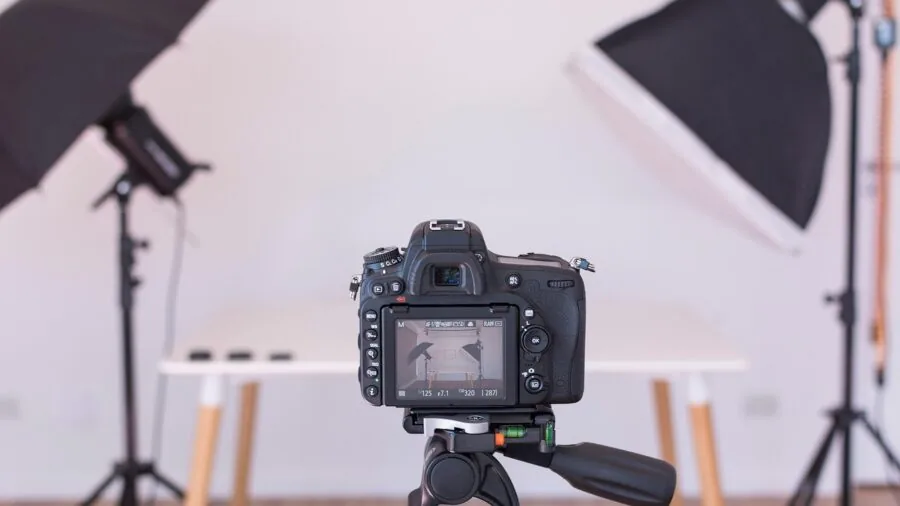 Professional photographer adjusting off-camera flash equipment in creative studio lighting setup