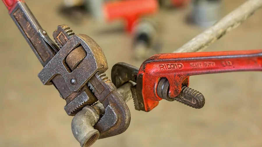 Professional plumber working on pipe connections with adjustable wrench in realistic workshop setting