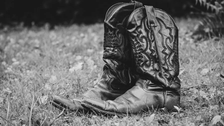 Professional wearing durable leather work boots on wet job site with water droplets