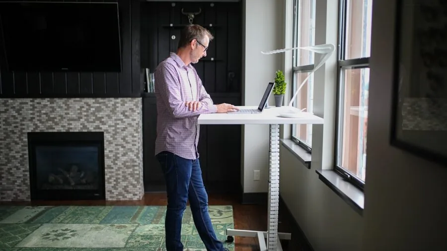 Professional working at standing desk in modern office with focus on posture and leg position