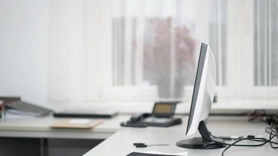 Professional working on laptop at a clean desk with coffee and notebook in a bright home office environment
