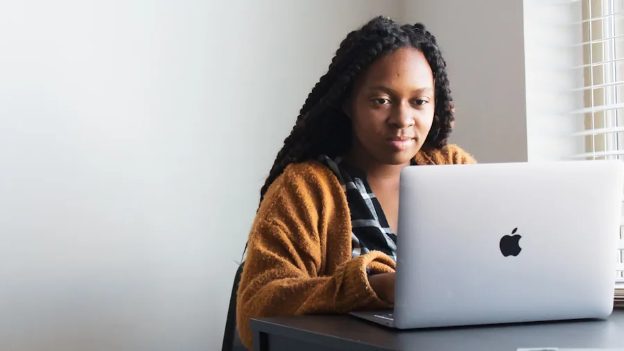 Professional working on laptop at desk with focused expression while reviewing information
