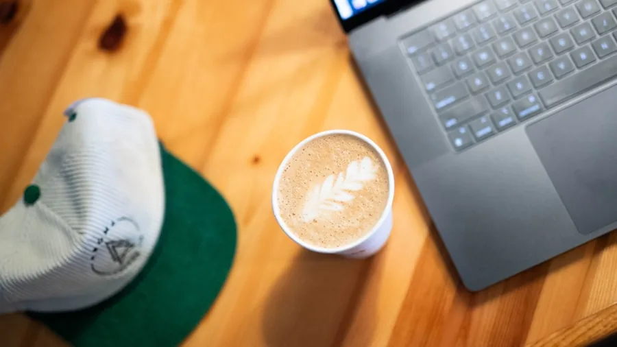 Professional working on laptop at outdoor cafe with coffee, showing real-world laptop usage and battery life