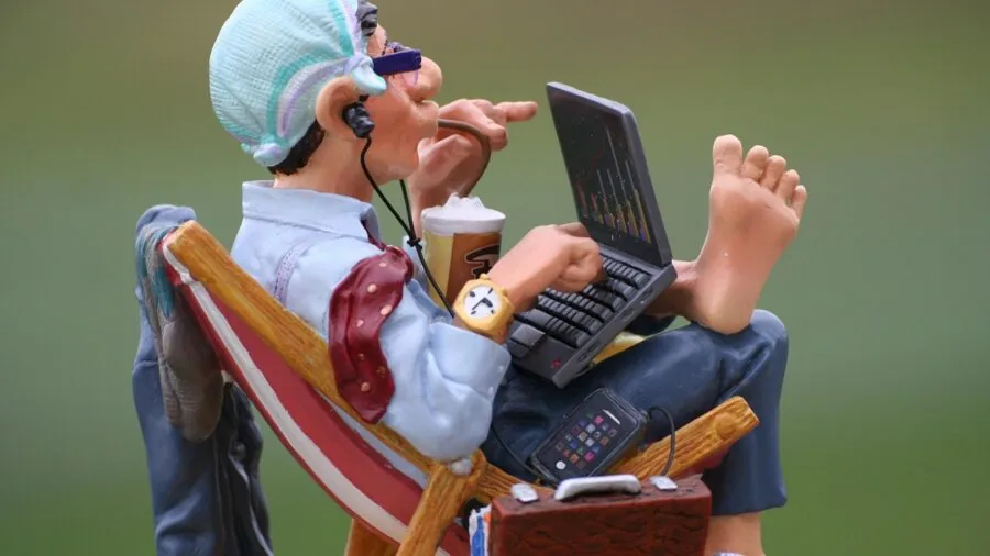 Remote worker using laptop at a coffee shop table with a beverage nearby