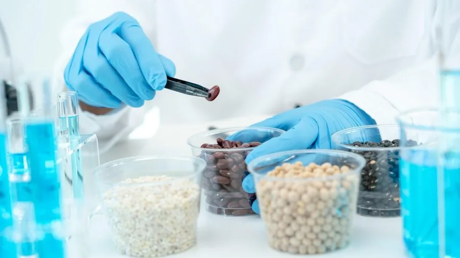 Researcher examining water sample in laboratory setting with scientific equipment and testing apparatus