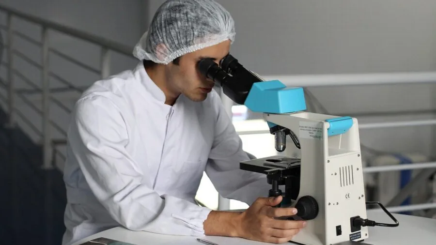 Researcher looking through microscope lens at laboratory specimen in scientific workplace
