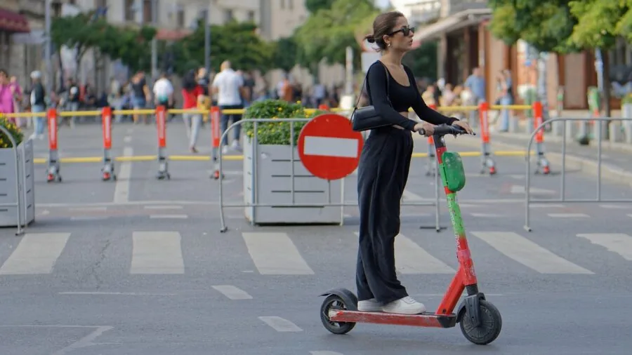 Rider on electric scooter commuting through city streets during daytime