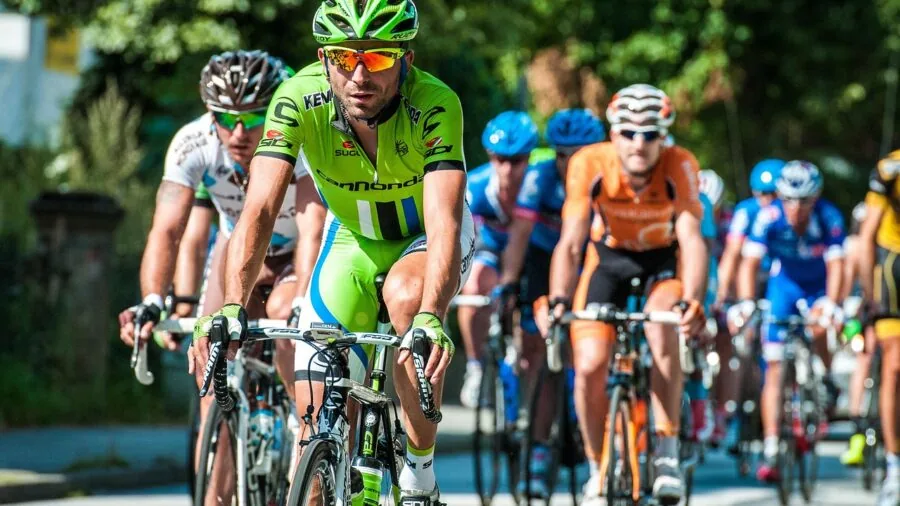 Road cyclist in racing gear riding bike on outdoor course, focused on speed and performance