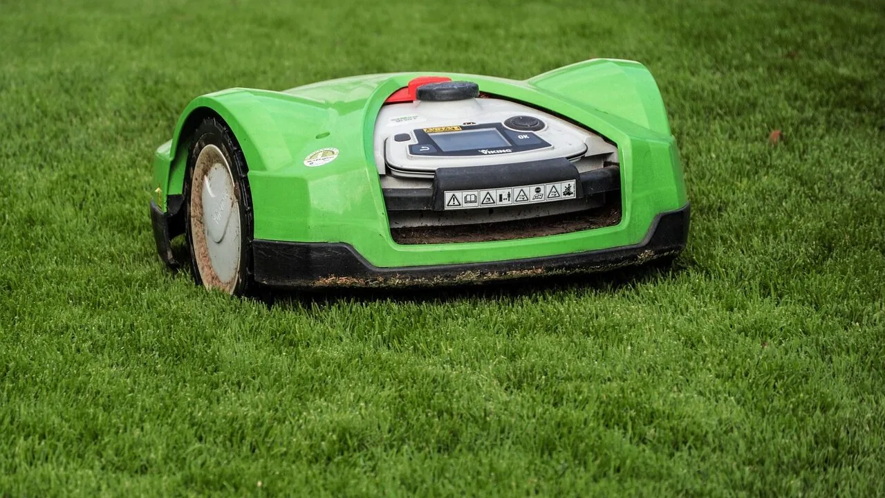 Robotic lawn mower autonomously mowing residential lawn with grass clippings visible