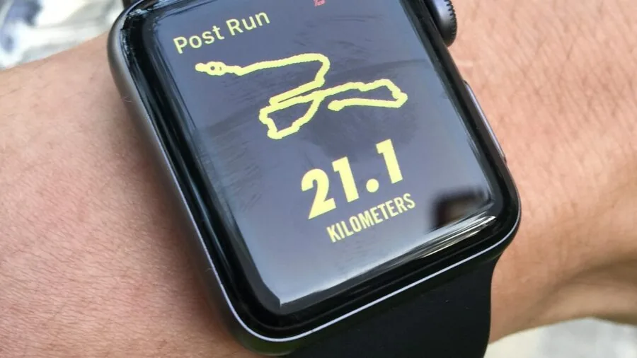 Runner checking smartwatch battery before evening run on urban path