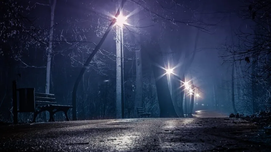Runner jogging on dark path at night with reflective visibility in low light conditions