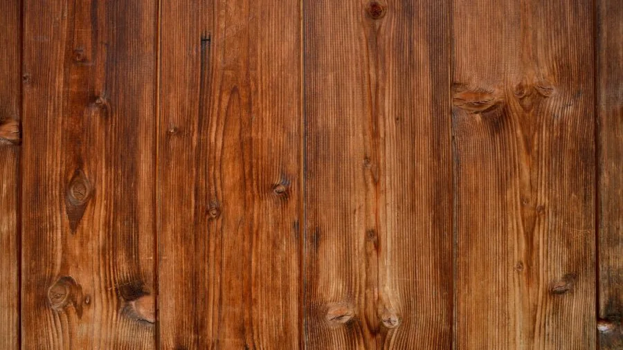 Rustic wooden playhouse standing in a backyard during rainy weather, showing natural wood aging and weather resistance
