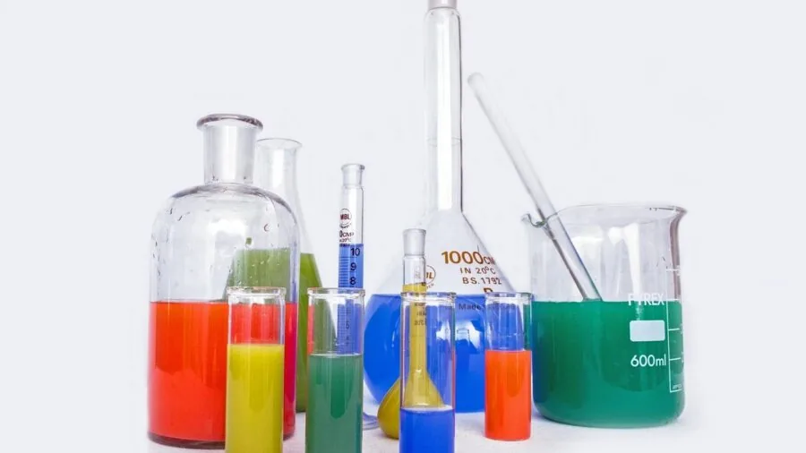 Scientist carefully pouring liquid into glass beaker during laboratory experiment