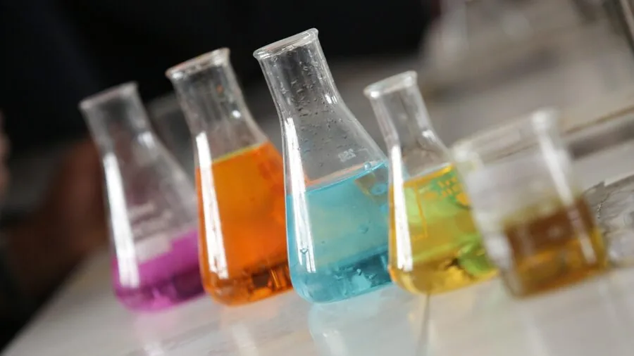 Scientist handling chemical-resistant materials in modern lab setting with various testing equipment