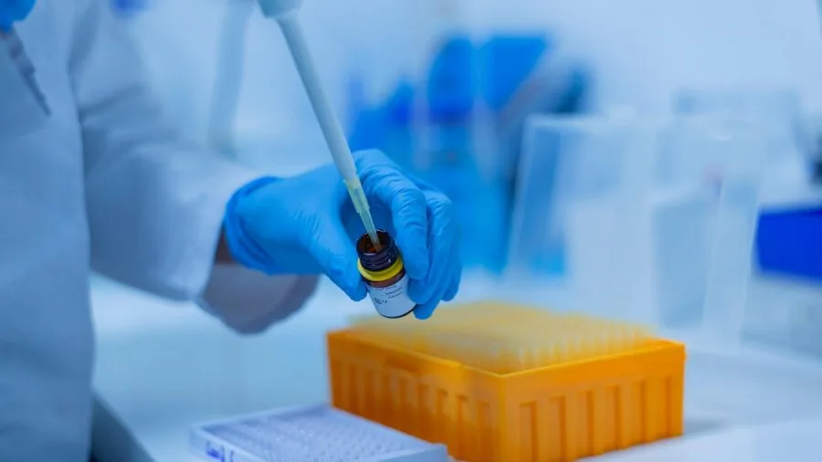 Scientist in lab coat carefully handling pipette during precision liquid transfer experiment