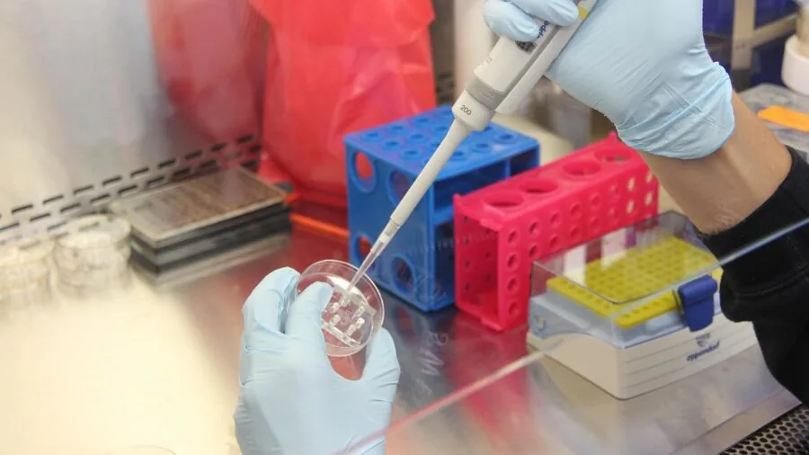 Scientist in lab coat conducting equipment testing and analysis at workbench with precision instruments
