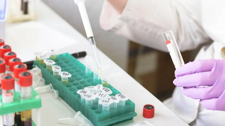 Scientist in lab coat using thermometer to measure temperature during experimental work in modern laboratory setting