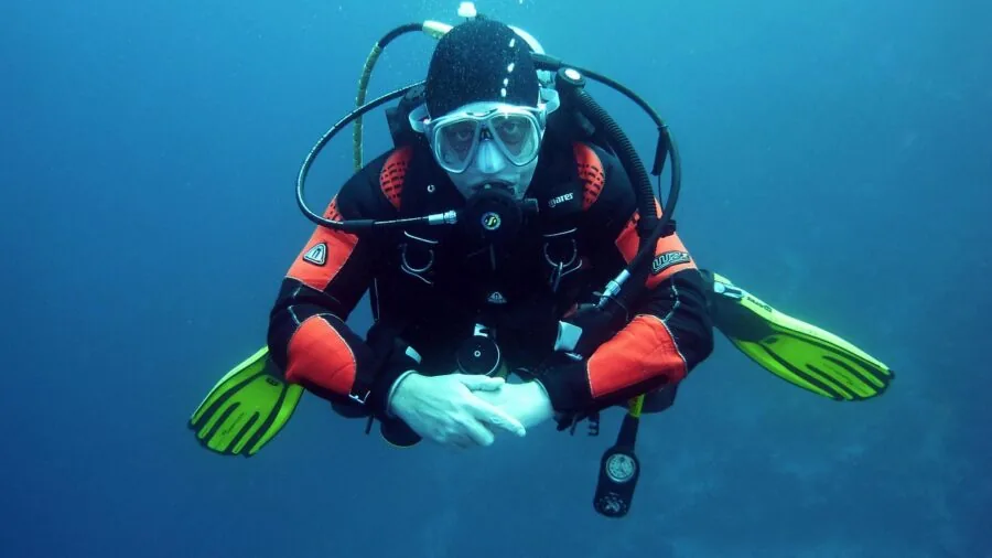 Scuba diver examining wristwatch during underwater dive exploration