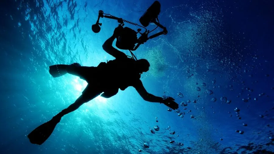 Scuba diver exploring coral reef with clear underwater visibility and ocean landscape