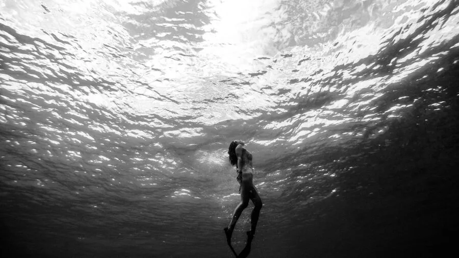 Scuba diver exploring underwater reef with clear blue water and natural sunlight filtering through