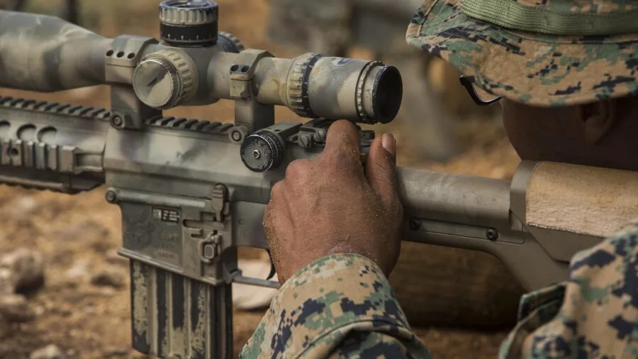 Shooter attaching optical sight to rifle at outdoor range for hunting preparation