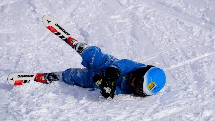 Skier in winter gear adjusting goggles while looking at snowy mountain landscape