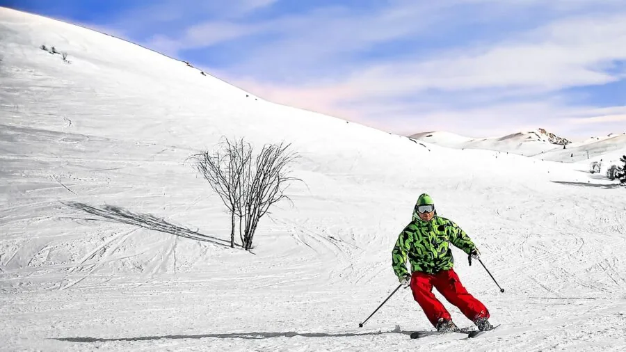 Skier in winter gear adjusting ski goggle lenses on snowy alpine slope